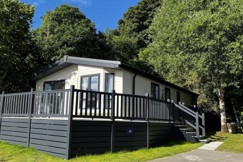 Outside View of a Luxury Lodge with a Decking area surrounded by Trees