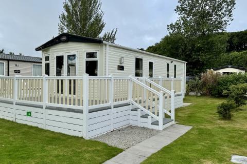 Outside View of a Caravan Holiday Home with a Decking area surrounded by Trees