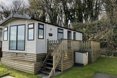 Outside View of a Caravan Holiday Home with a Decking area surrounded by Trees