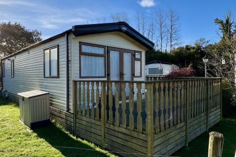 Outside View of a Caravan Holiday Home with a Decking area surrounded by Trees
