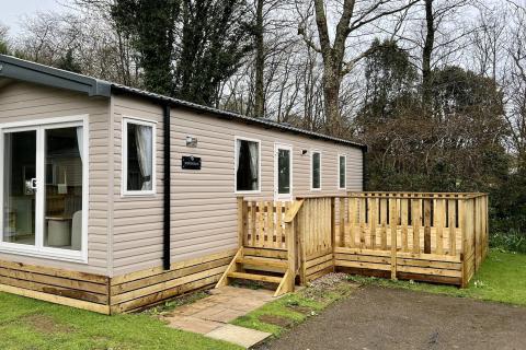 Outside View of a Caravan Holiday Home with a Decking area surrounded by Trees