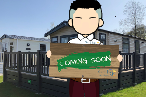 An Image of a Caravan Holiday Home with a Person holding a Coming Soon Sign