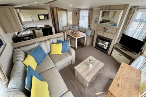 Interior view of the living room, with L shaped sofa, fireplace, TV and TV stand. 