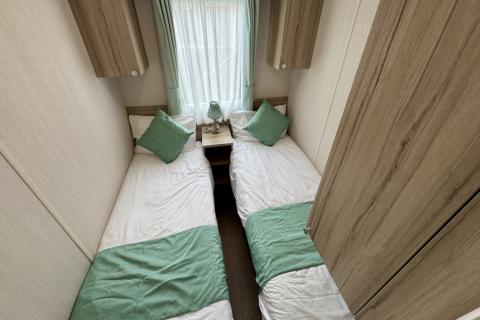 Twin bedroom with two single beds, bedside table and overbed storage. 