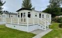Outside View of a Caravan Holiday Home with a Decking area surrounded by Trees