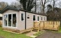 Outside View of a Caravan Holiday Home with a Decking area surrounded by Trees