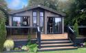 Outside View of a Luxury Lodge with a Decking area surrounded by Trees