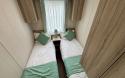 Twin bedroom with two single beds, bedside table and overbed storage. 