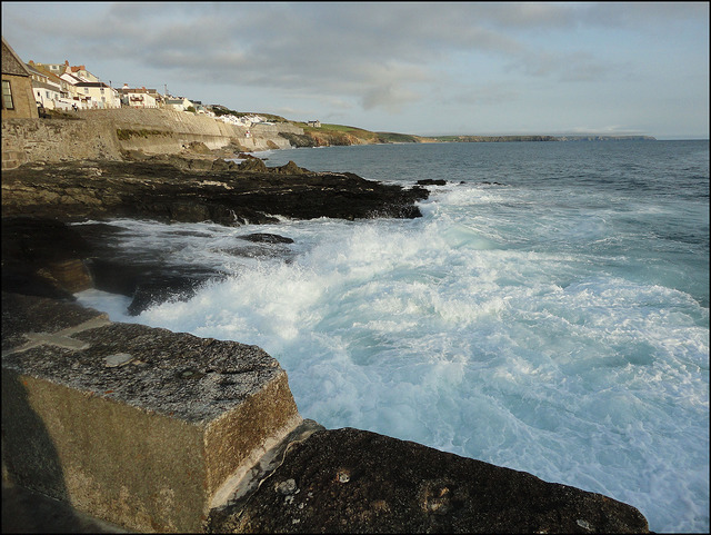 A Wave breaking onto a rocky shore with Sea Walls on the South Coast of Cornwall
