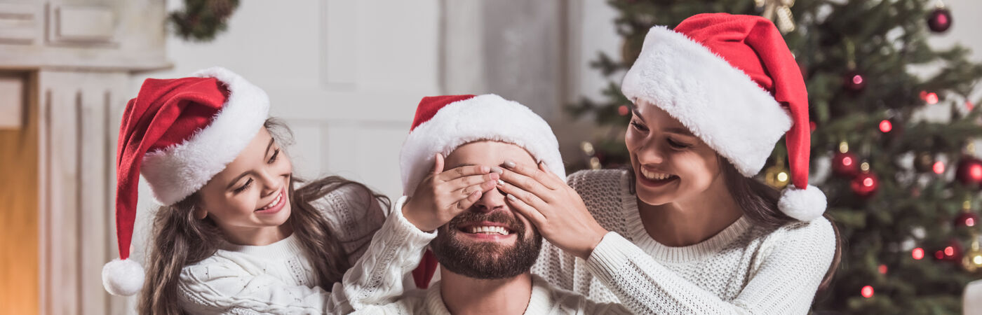 Three People wearing Santa hats in front of a Christmas Tree