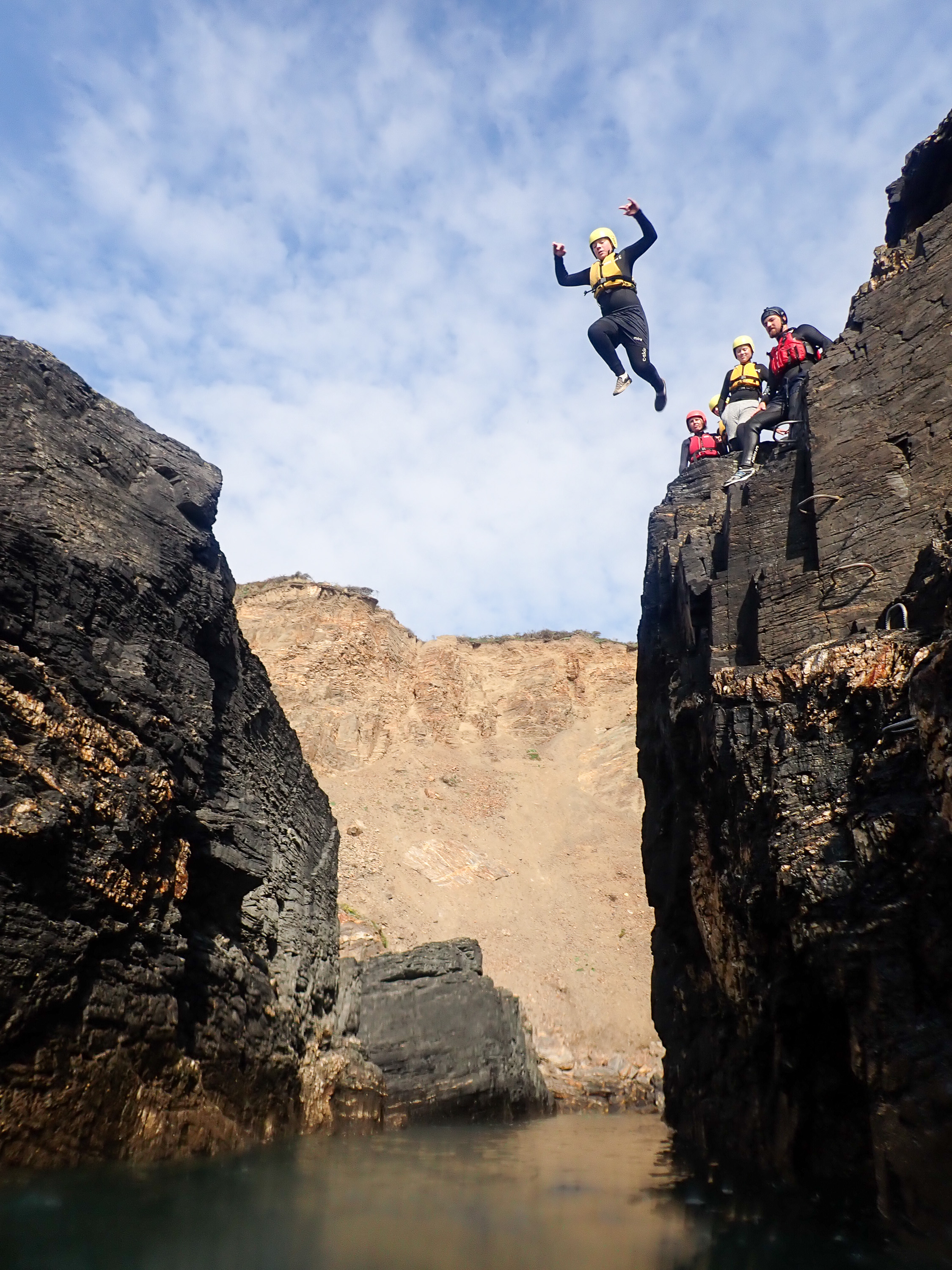 Person coasteering off a cliff in Cornwall
