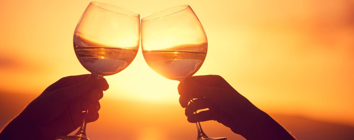 Wine glasses being clinked at sunset