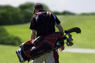 A Person Carrying a bag of Golf Clubs on a Golf Course