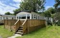 Outside View of a Caravan Holiday Home with a Decking area surrounded by Trees