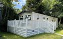Outside View of a Caravan Holiday Home with a Decking area surrounded by Trees
