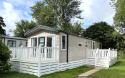Outside View of a Caravan Holiday Home with a Decking area surrounded by Trees