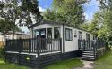 Outside View of a Caravan Holiday Home with a Decking area surrounded by Trees
