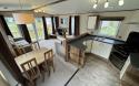 View of dining area with freestanding table and chairs, and open plan kitchen to the side.
