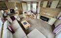 Interior view of the living area with L shaped sofa, coffee table, TV stand and fireplace.